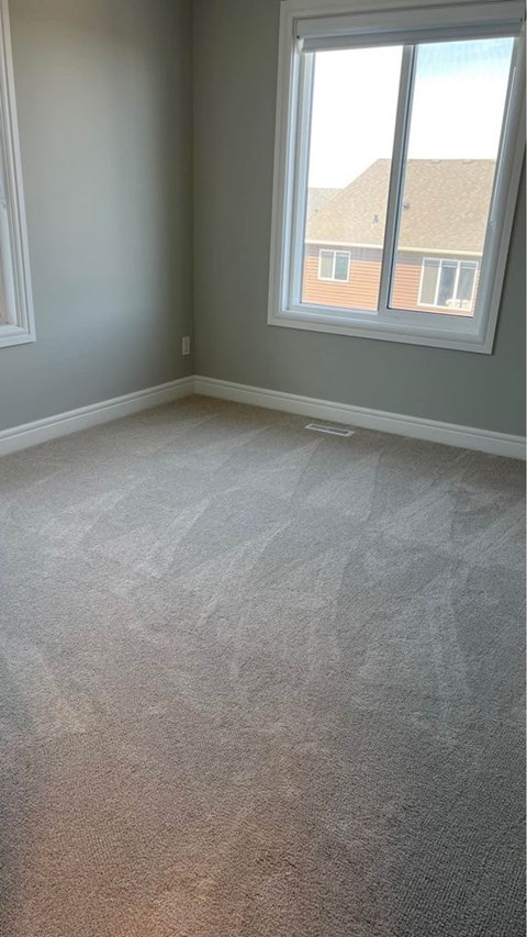 an empty room with a carpeted floor and two windows