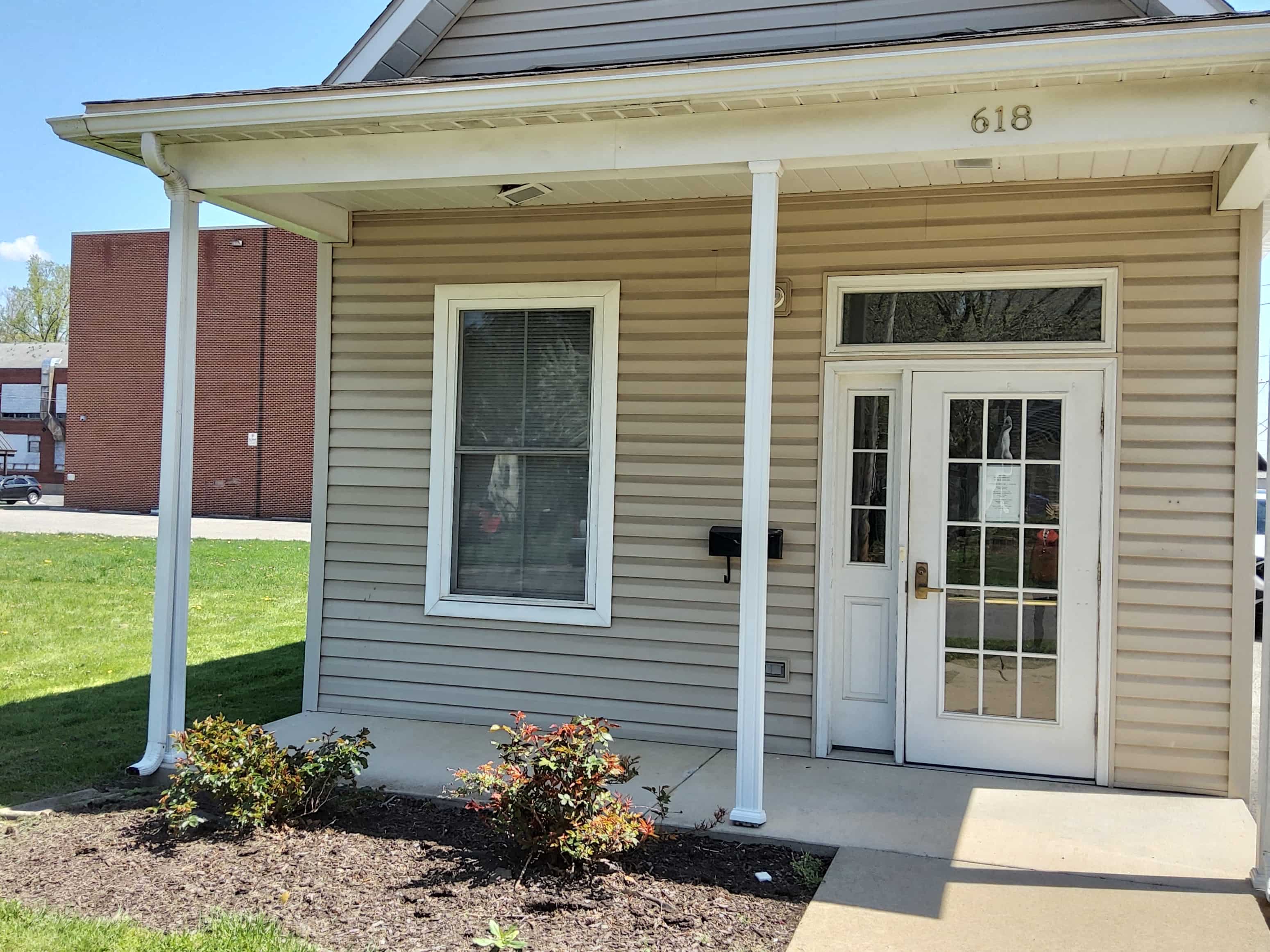 the front of a tan house with a white door