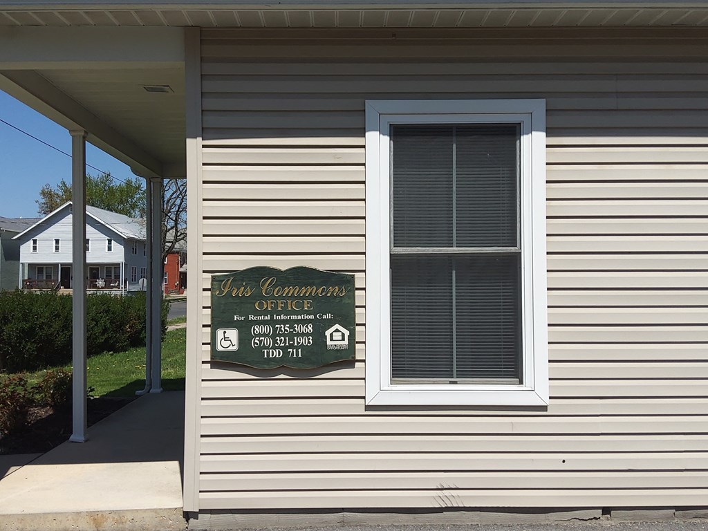 a sign on the side of a white house with a window