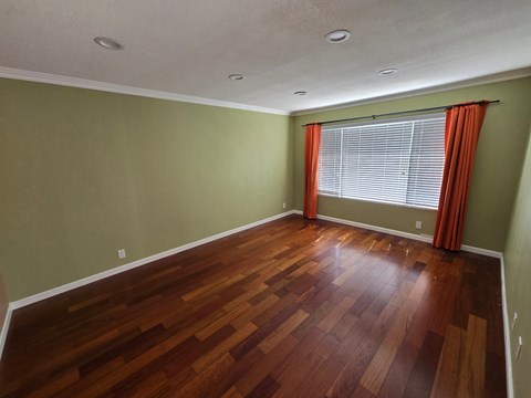 a living room with wood floors and a large window with a curtain
