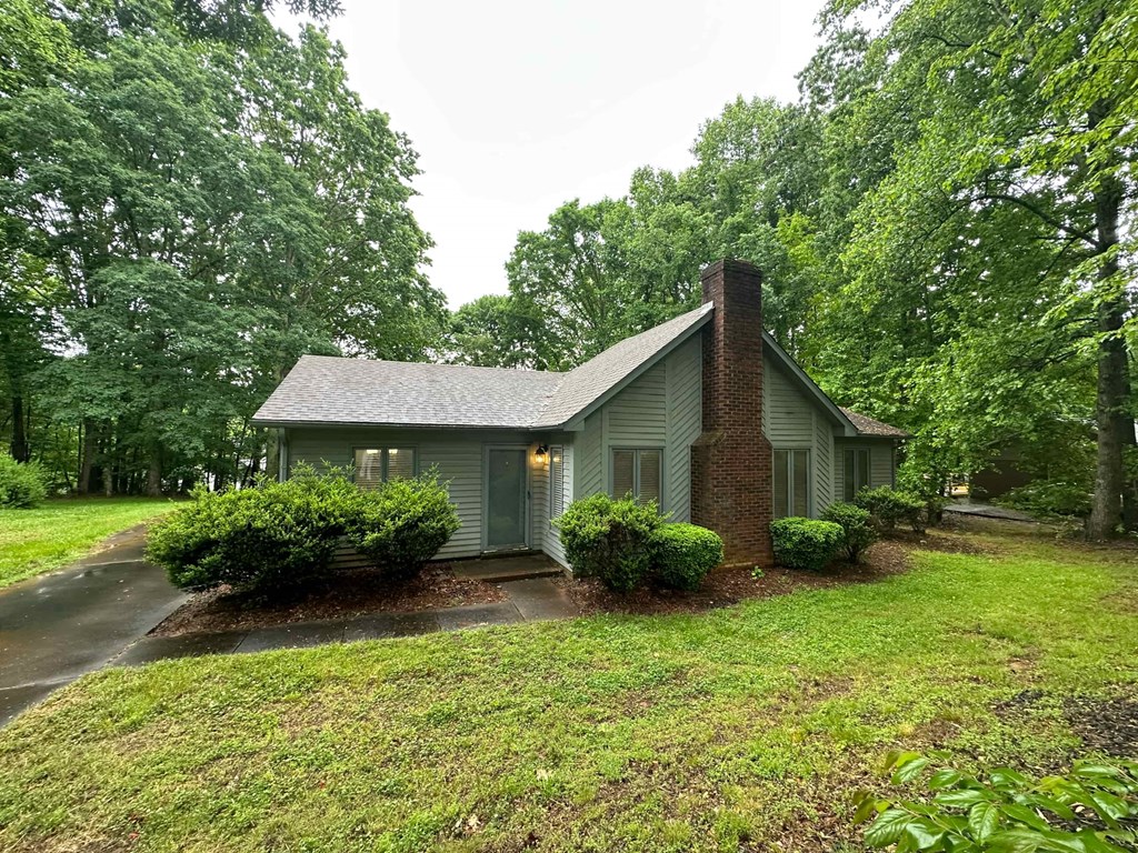 a small green house with a driveway and trees