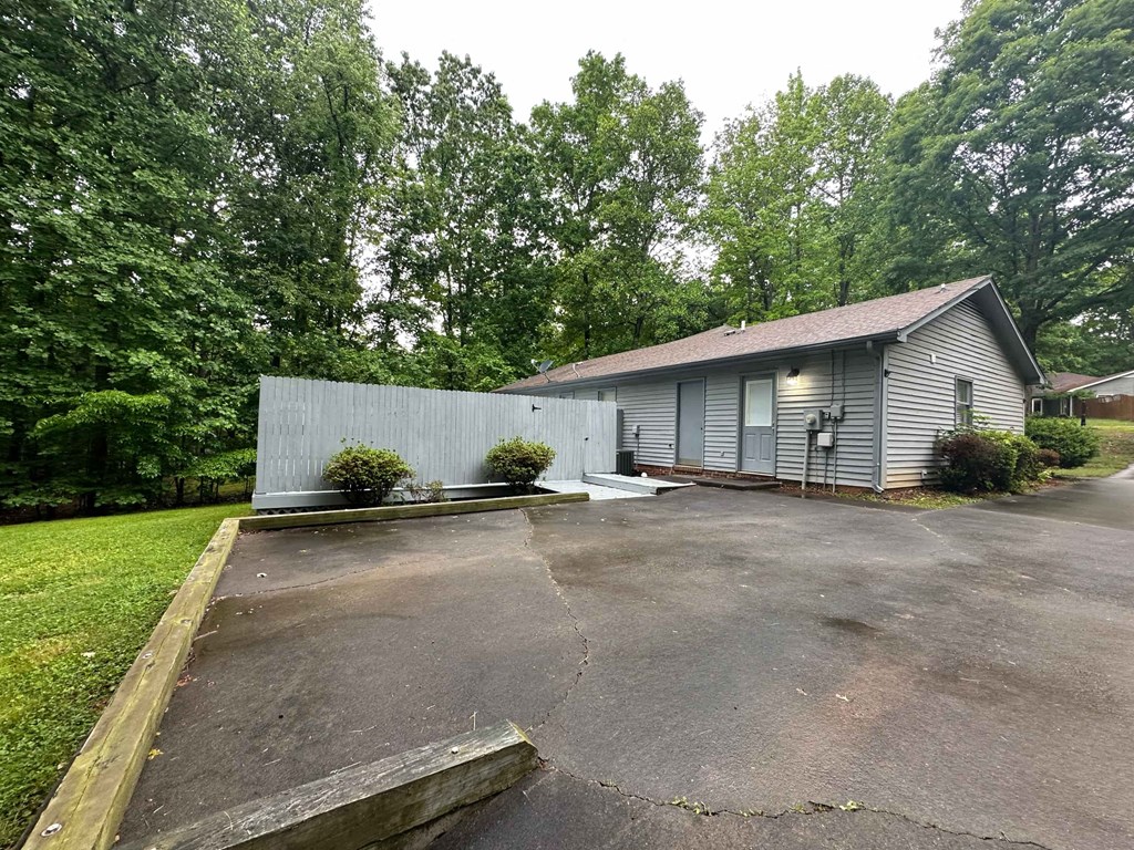 a small gray house with a driveway and a parking lot