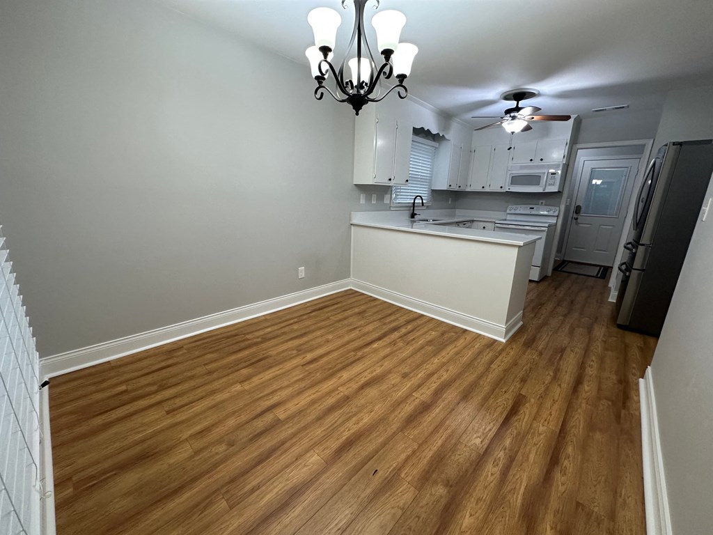 a living room and kitchen with wood flooring and a chandelier