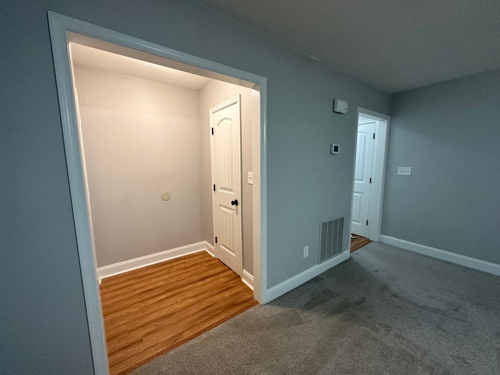 a bedroom with a door and a hallway with a wood floor