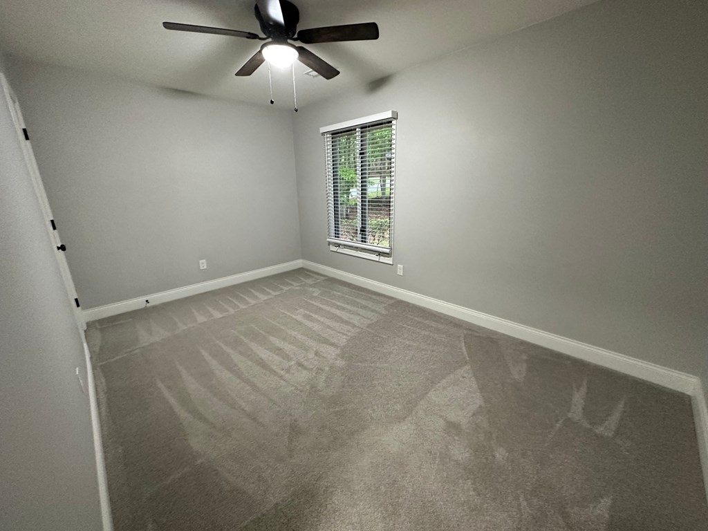 a empty room with a ceiling fan and a window