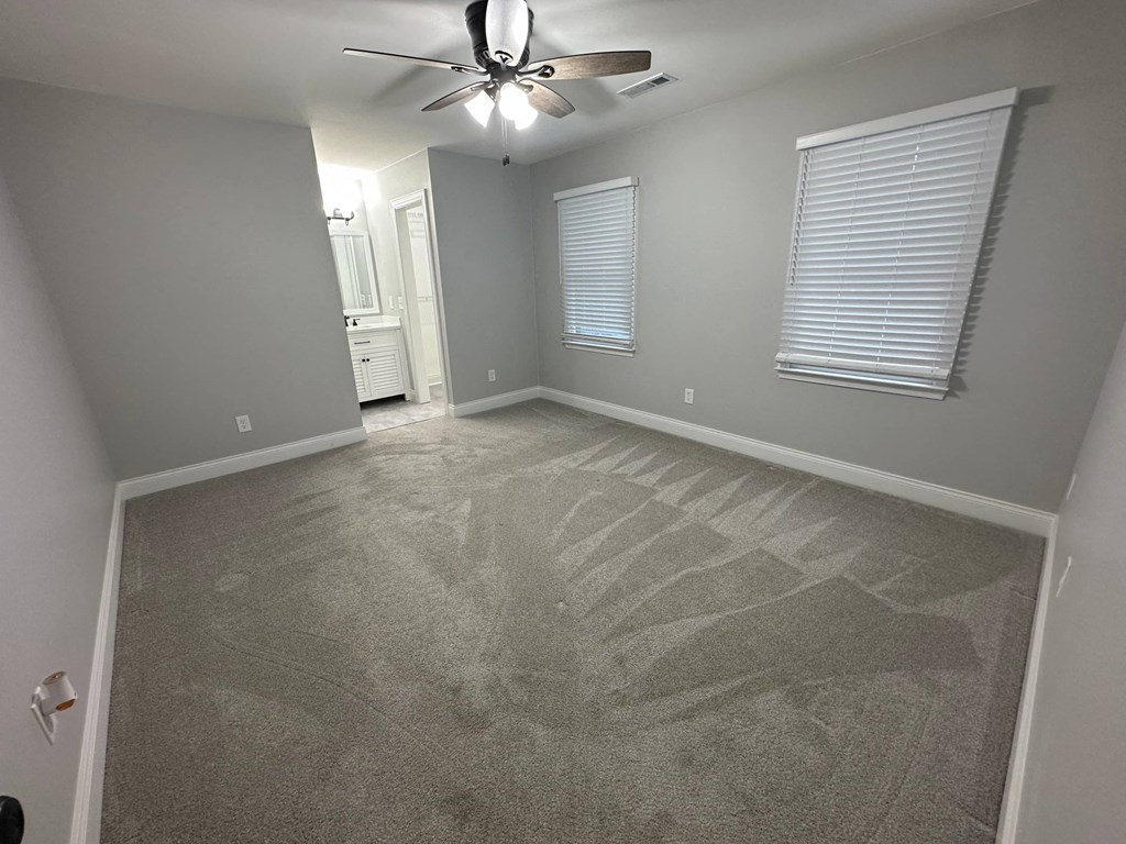 a bedroom with a carpeted floor and a ceiling fan