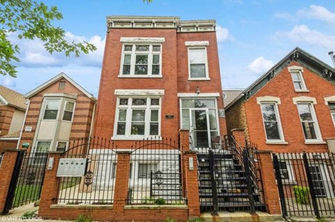 a red brick house with a wrought iron fence