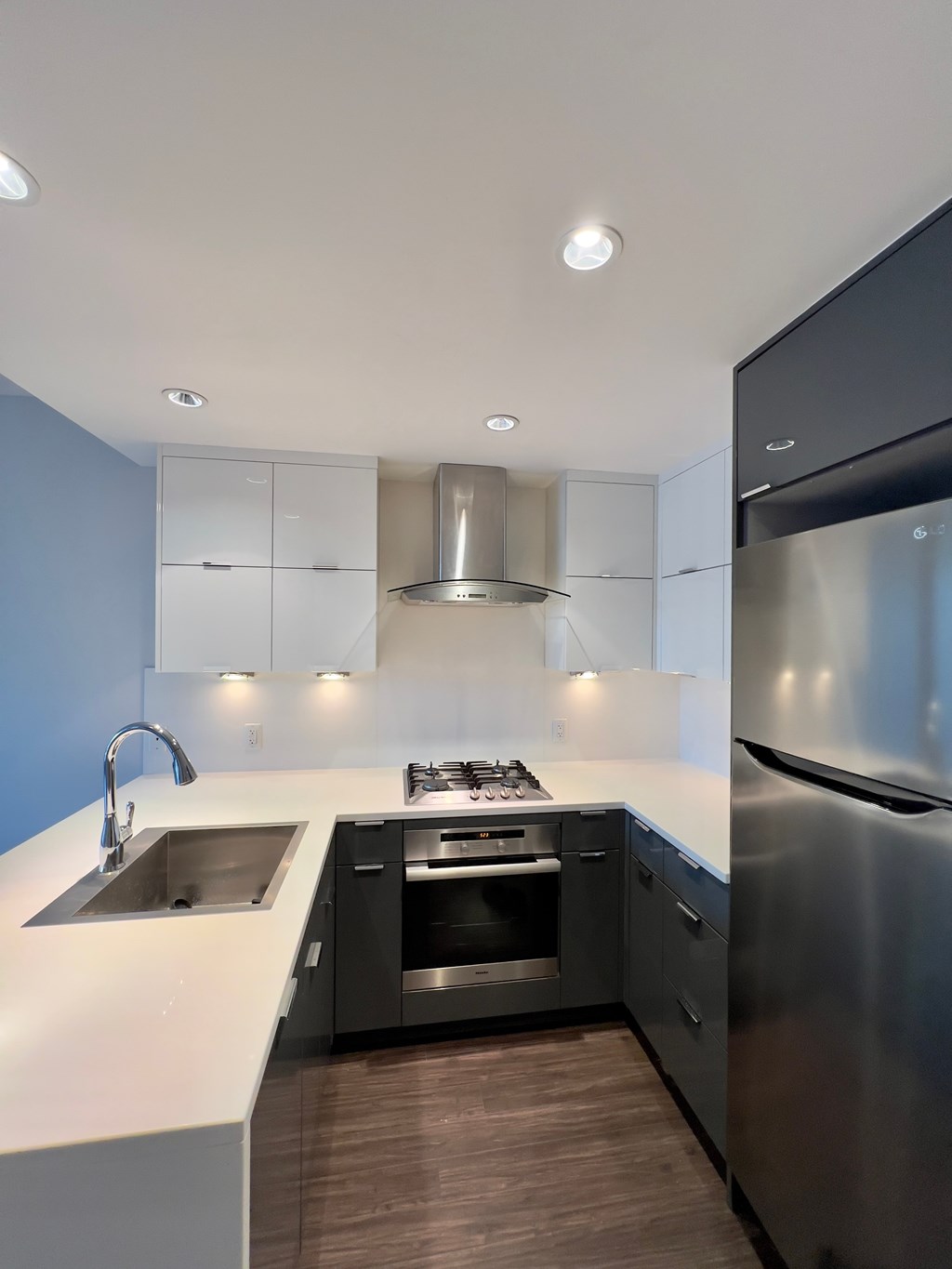 A modern kitchen with a stainless steel refrigerator and a sink.