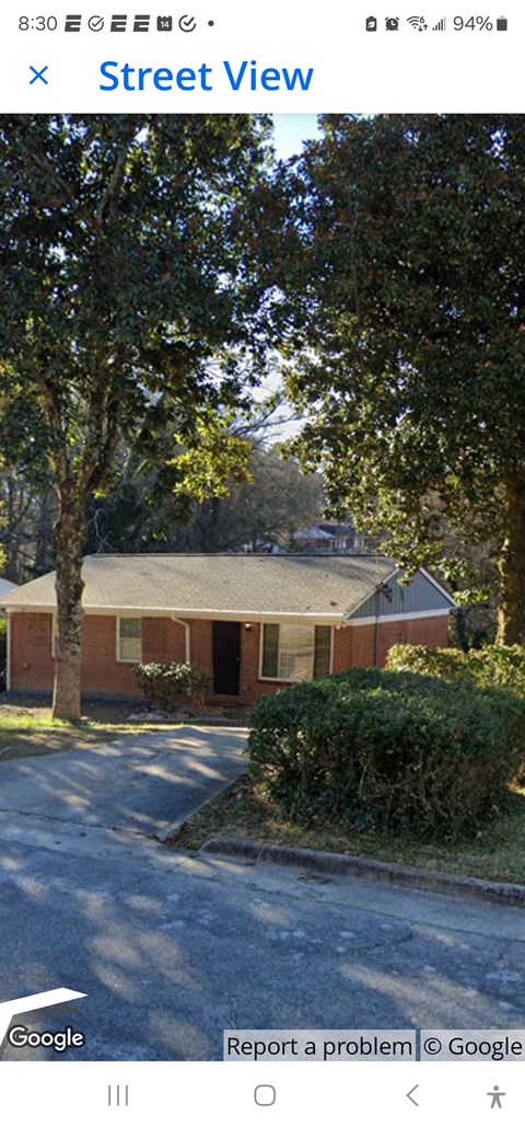 A street view of a residential area with houses and trees.