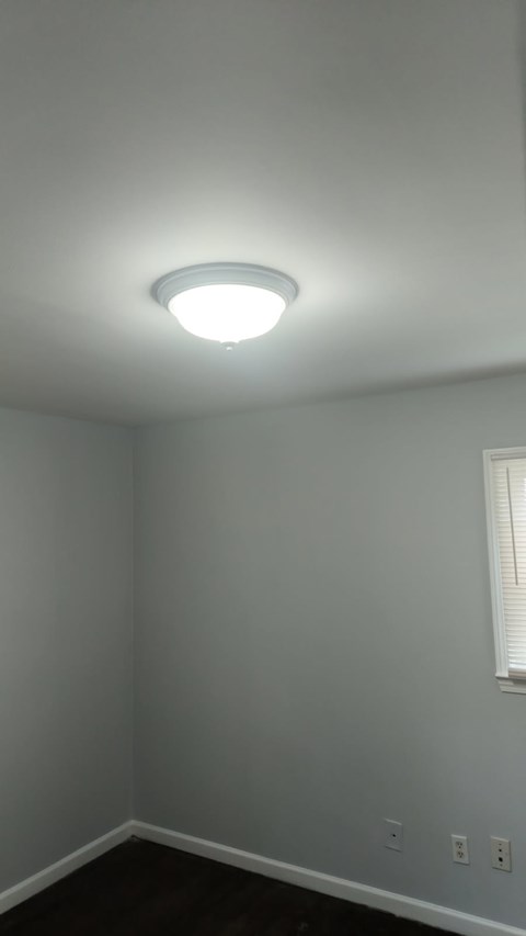 A white ceiling light in a room with white walls and a window.