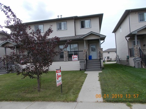 A house with a sign that says "For Sale" in front of it.