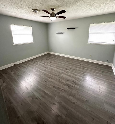 an empty living room with wood floors and a ceiling fan
