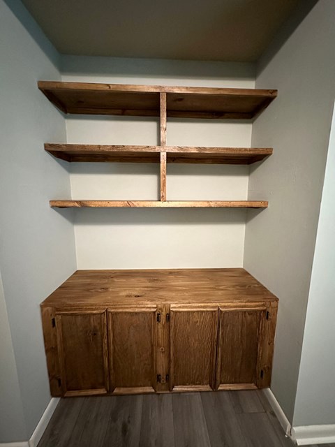 a dresser with shelving and two shelves on the wall