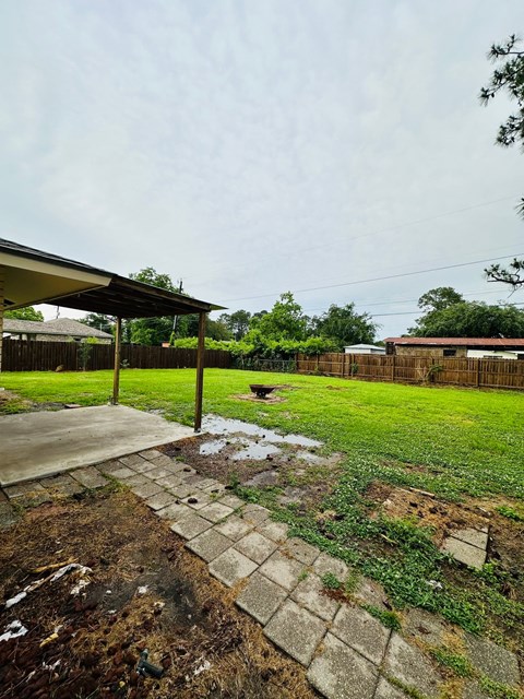 a yard with grass and a sidewalk and a fence