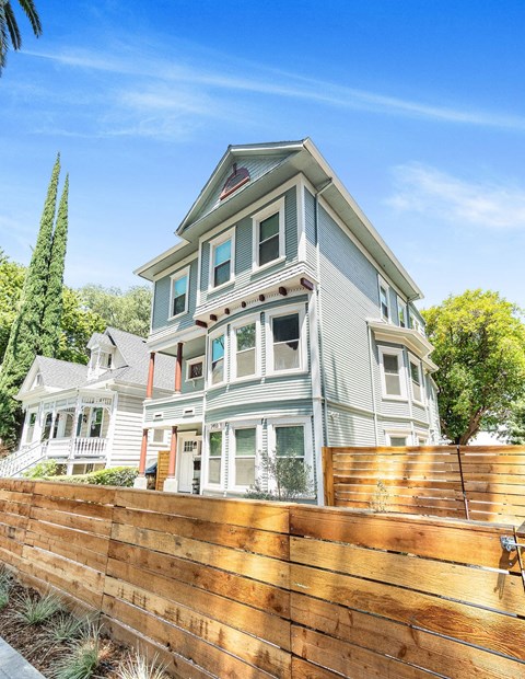 A house with a grey facade and a wooden fence in front.