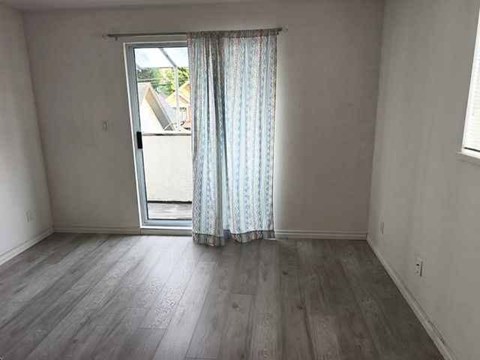 A room with a sliding glass door and a window with curtains.
