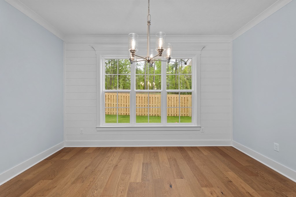 an empty living room with a window and a chandelier