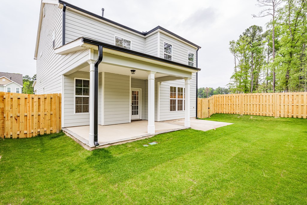a white house with a porch and a grassy yard and a wooden fence