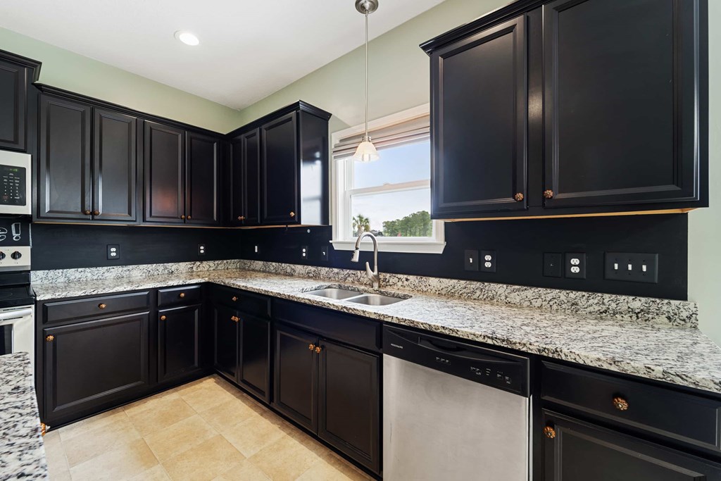 A kitchen with black cabinets and granite countertops.