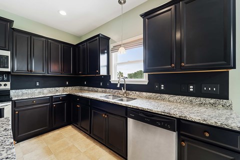 A kitchen with black cabinets and granite countertops.