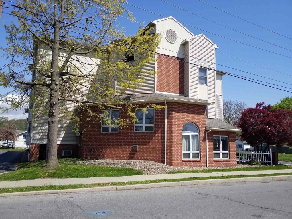 a brick house with a white roof and a tree in front of it