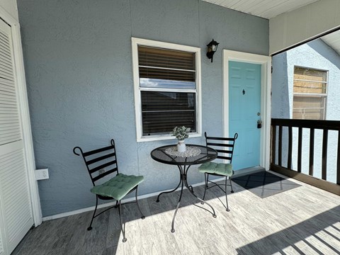 a porch with a table and chairs and a blue door