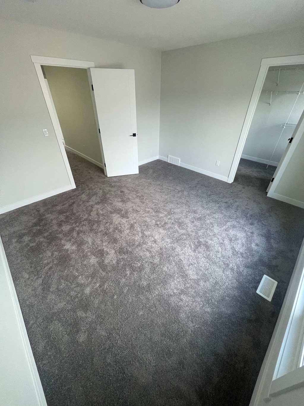 a carpeted room with white closets and a gray floor