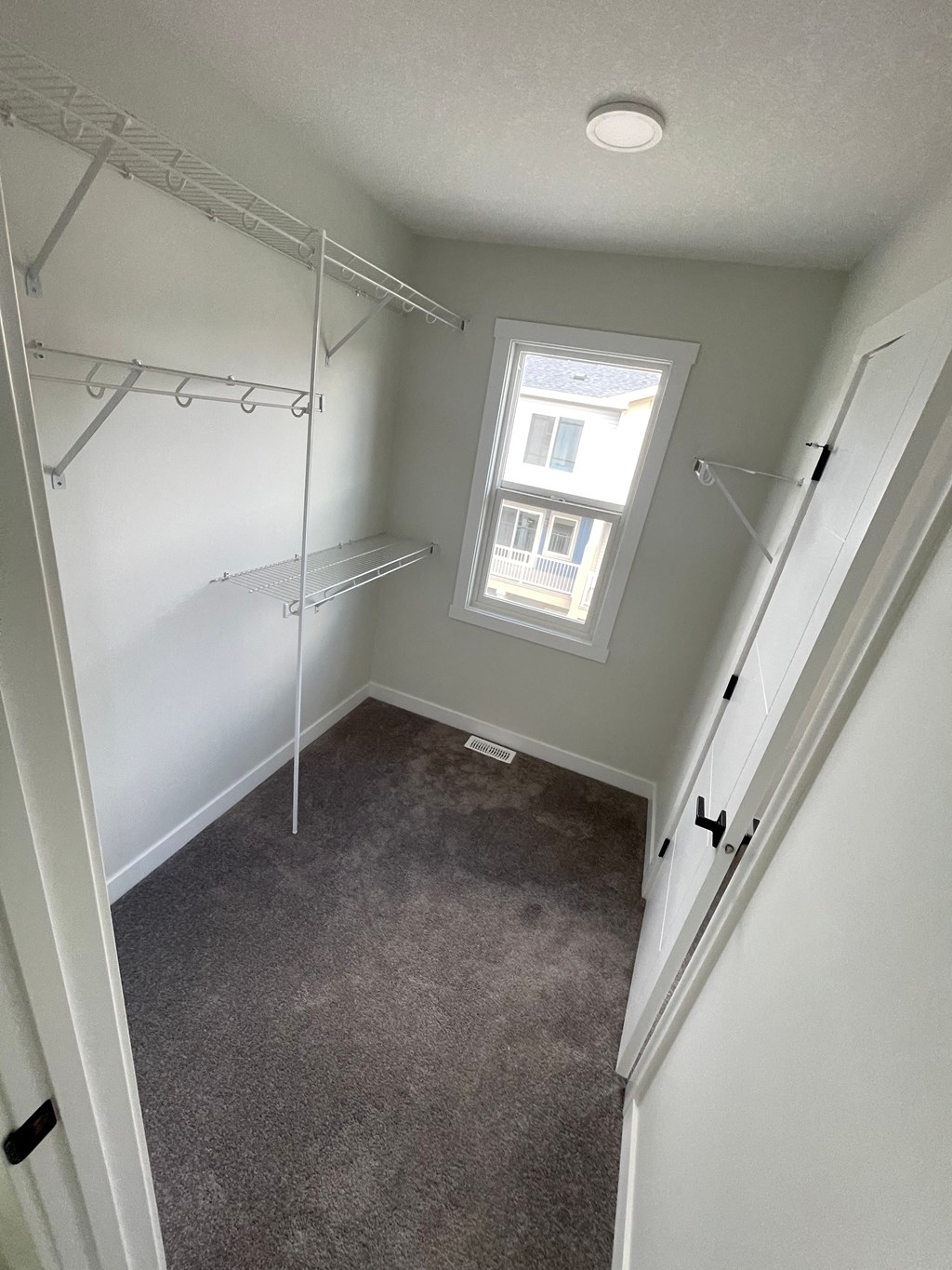 a walk in closet with a window and white walls