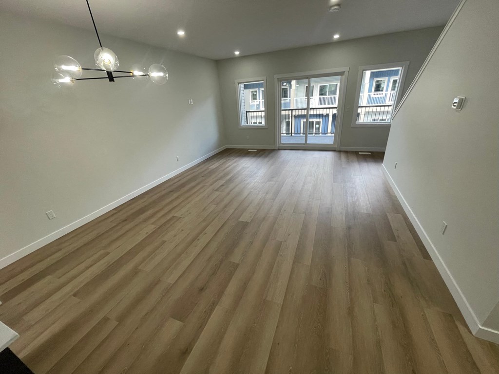an empty living room with hardwood floors and a large window
