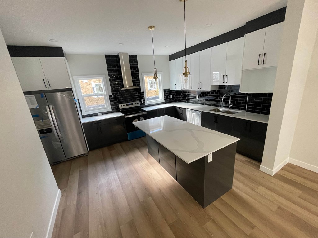 a large kitchen with black and white cabinets and stainless steel appliances