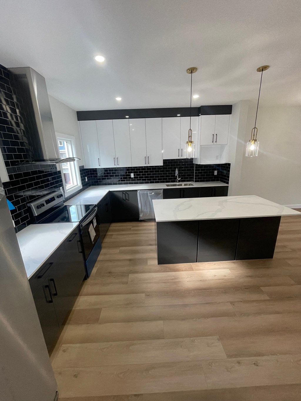 a view of a kitchen with black and white cabinets and a wooden floor
