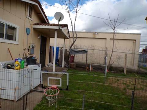 A backyard with a basketball hoop and a fence.