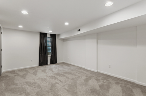 an empty living room with white walls and a window and curtains