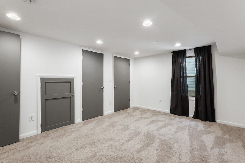 an empty living room with black curtains and white walls and a gray door