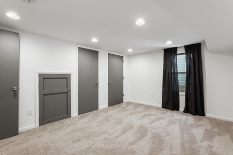 an empty living room with black curtains and white walls and a gray door