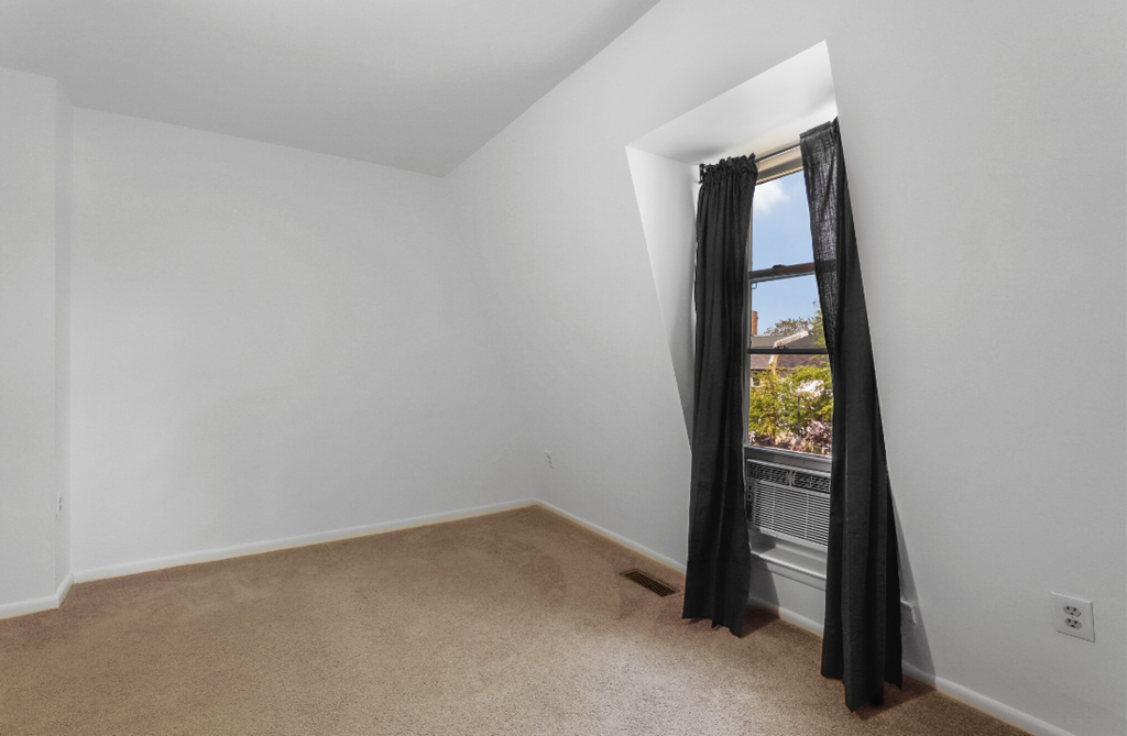 an empty room with a window and a black curtain