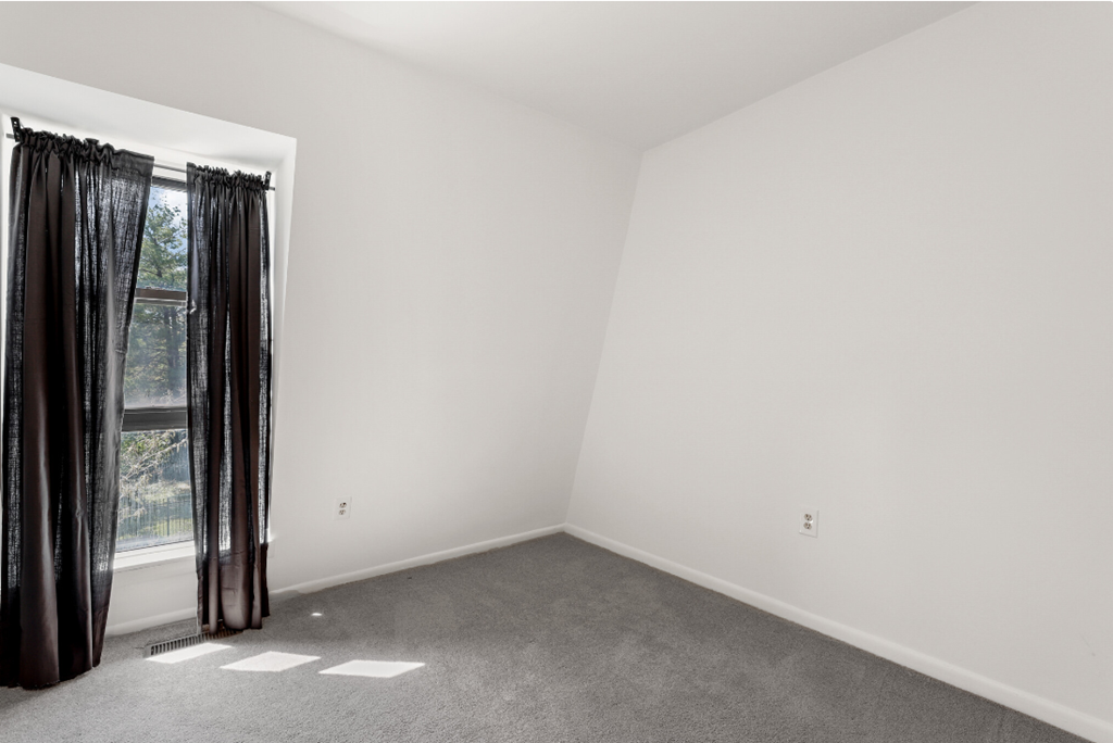 a room with white walls and a window with black curtains