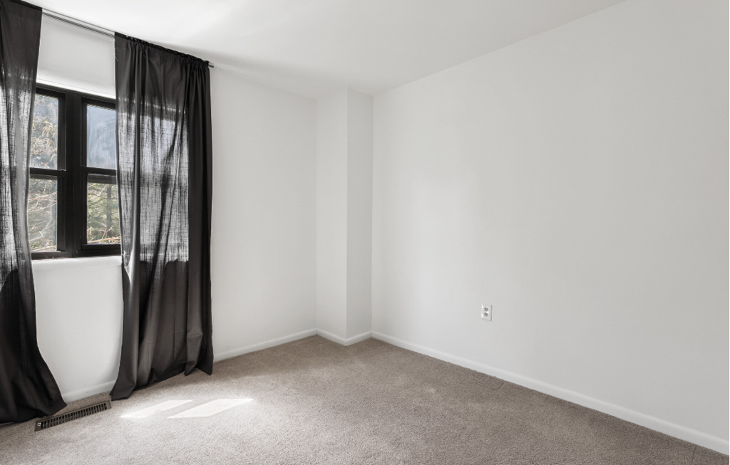 an empty room with white walls and a window