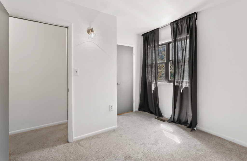 a living room with white walls and a window with a curtain
