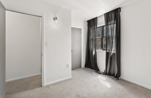 a living room with white walls and a window with a curtain