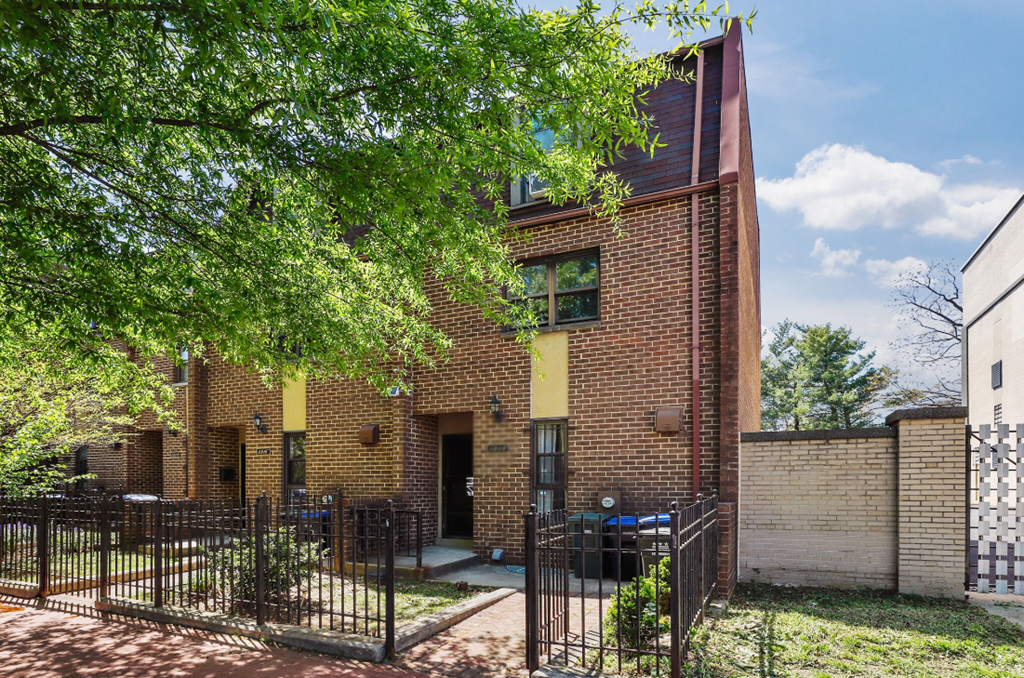 the front of a brick house with a gate and a tree