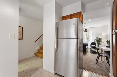 a kitchen with a stainless steel refrigerator and a living room with stairs