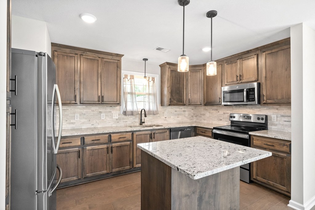 a kitchen with wooden cabinets and a marble counter top
