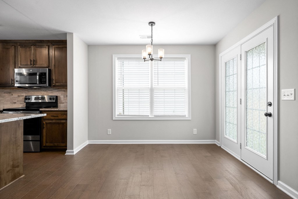 an empty living room with a window and a kitchen
