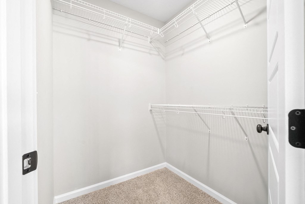 a spacious closet in a home with white walls and a white door