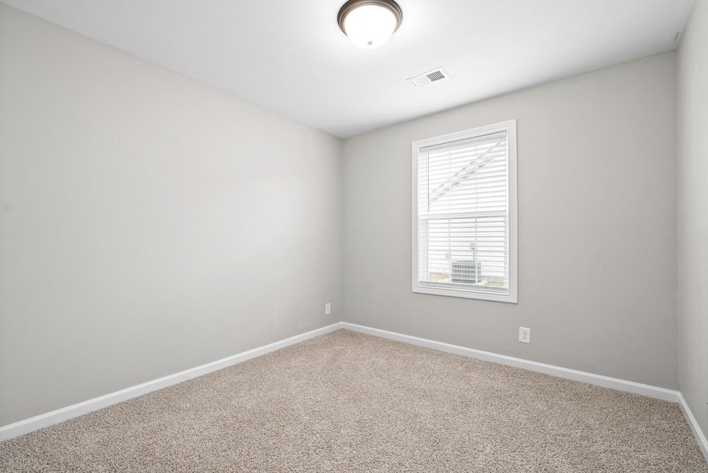 an empty room with a window and carpet