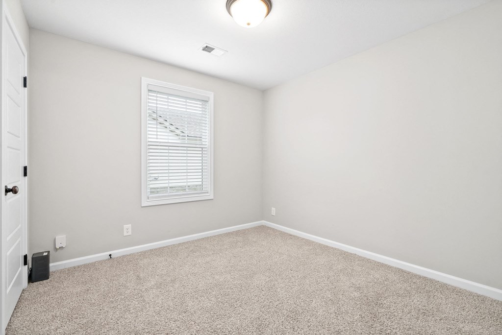 an empty room with carpet and a window