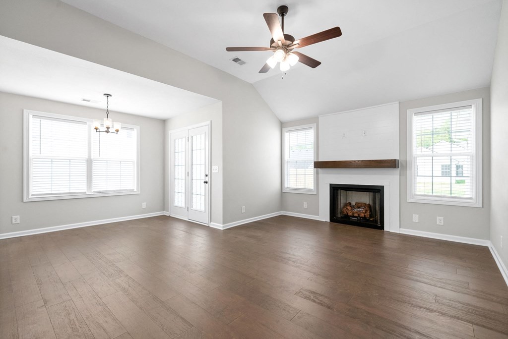 an empty living room with a ceiling fan and a fireplace