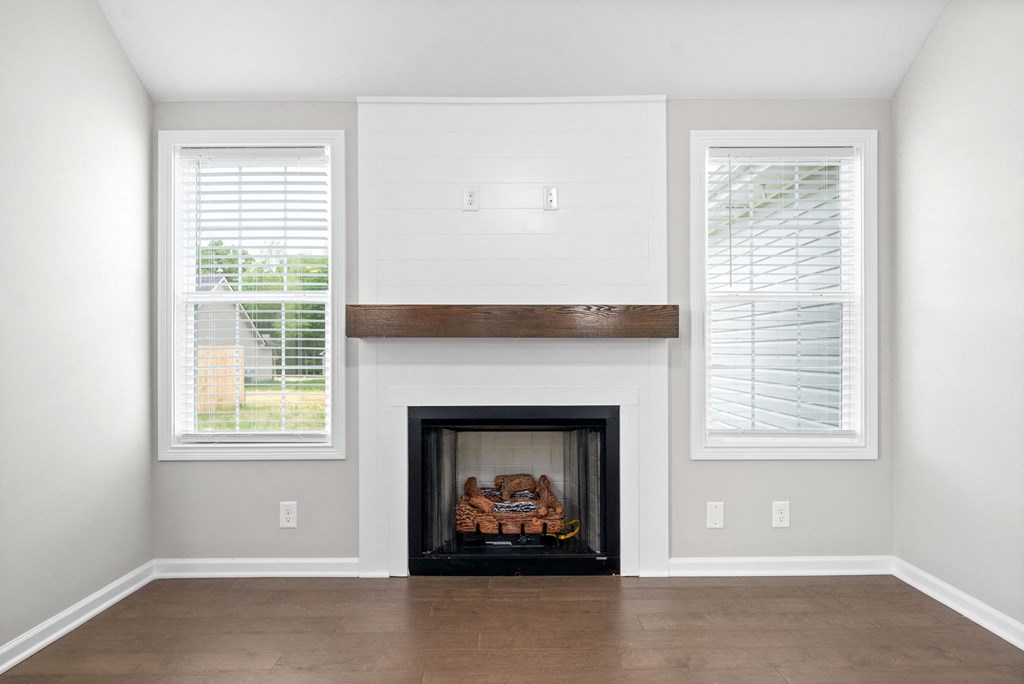 an empty living room with a fireplace and windows