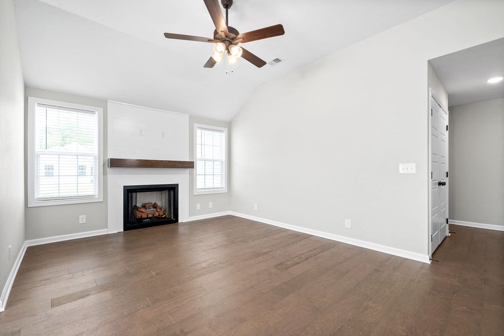 an empty living room with a ceiling fan and a fireplace